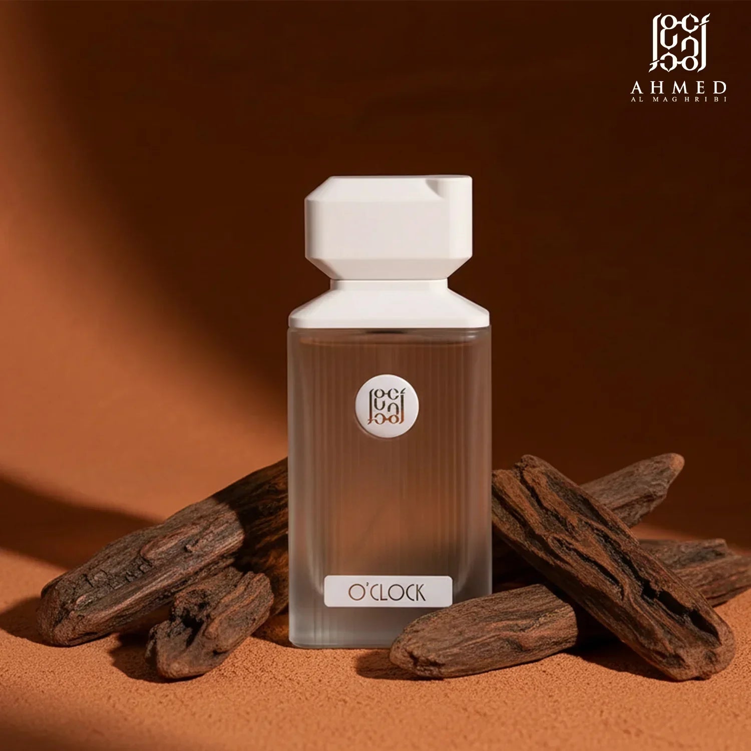 O'Clock perfume bottle with white cap, surrounded by oud wood on a brown background